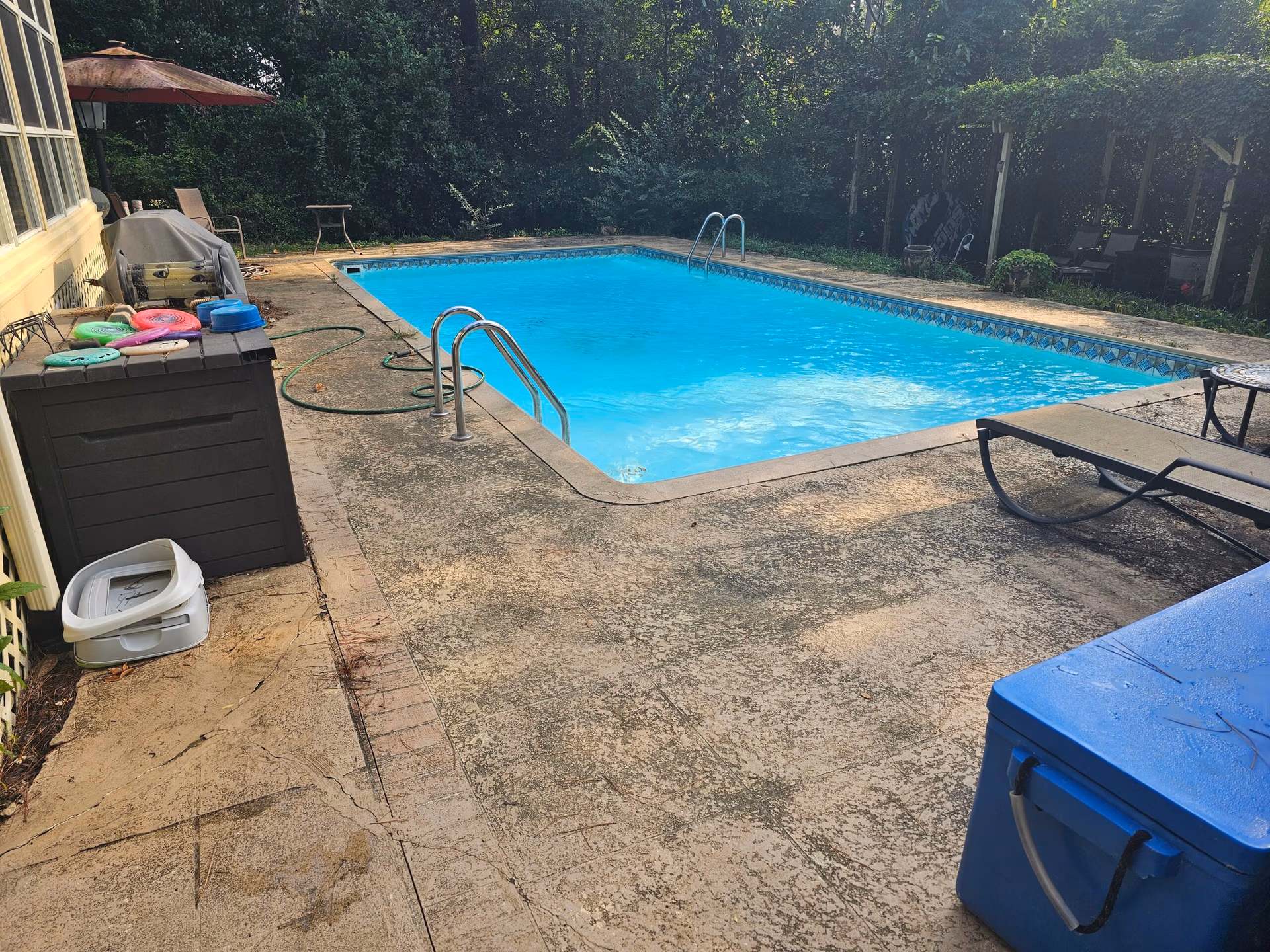 Pressure washed concrete pool deck surrounding a residential swimming pool with clean surfaces.