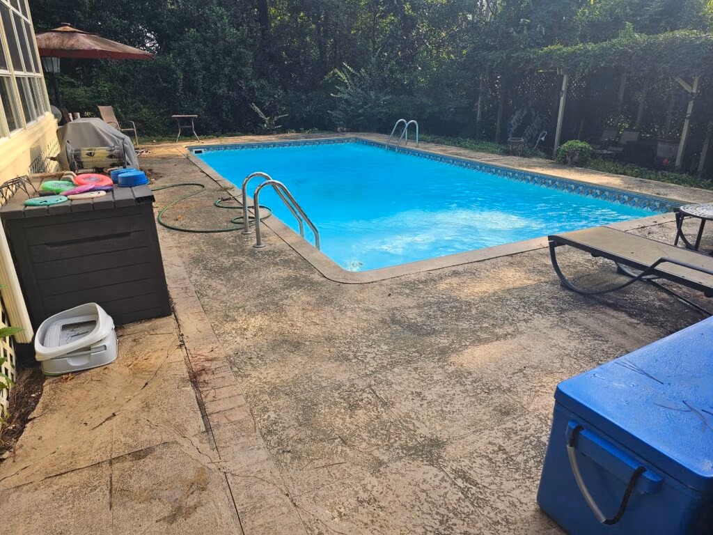 Pressure washed concrete pool deck surrounding a residential swimming pool.