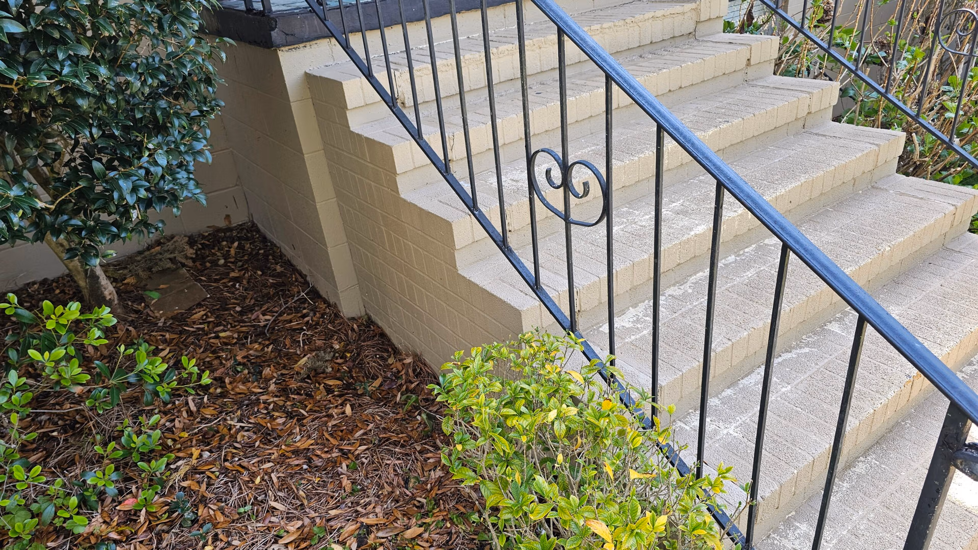 Concrete front steps with metal handrail leading to a residential home entrance