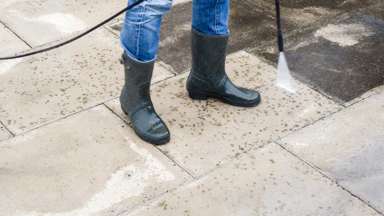 A pressure washer spraying outdoor pavers