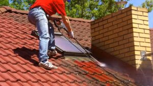 A man pressure washing a roof
