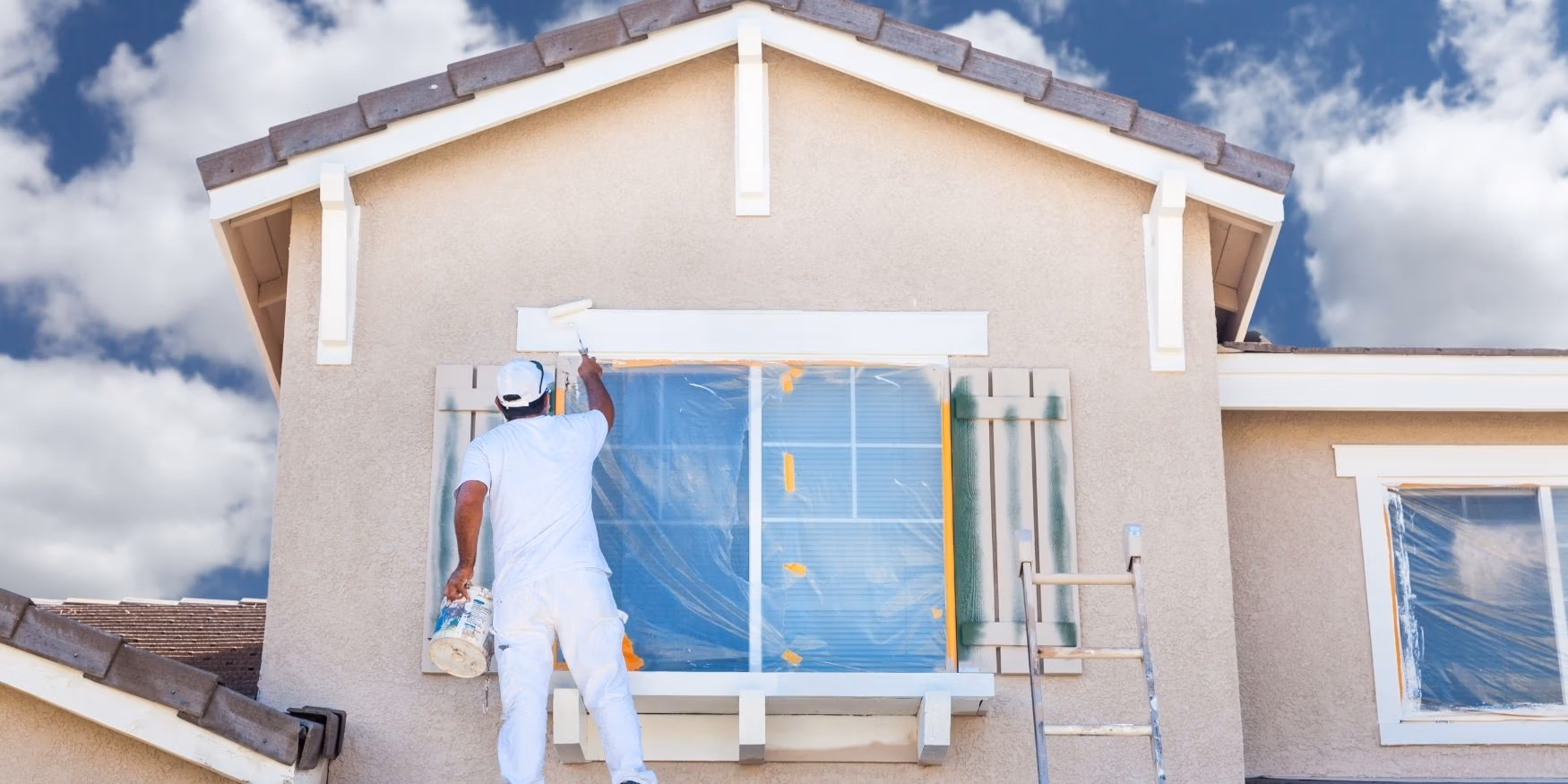 A painter prepping a clean home for a paint job after a recent pressure washing