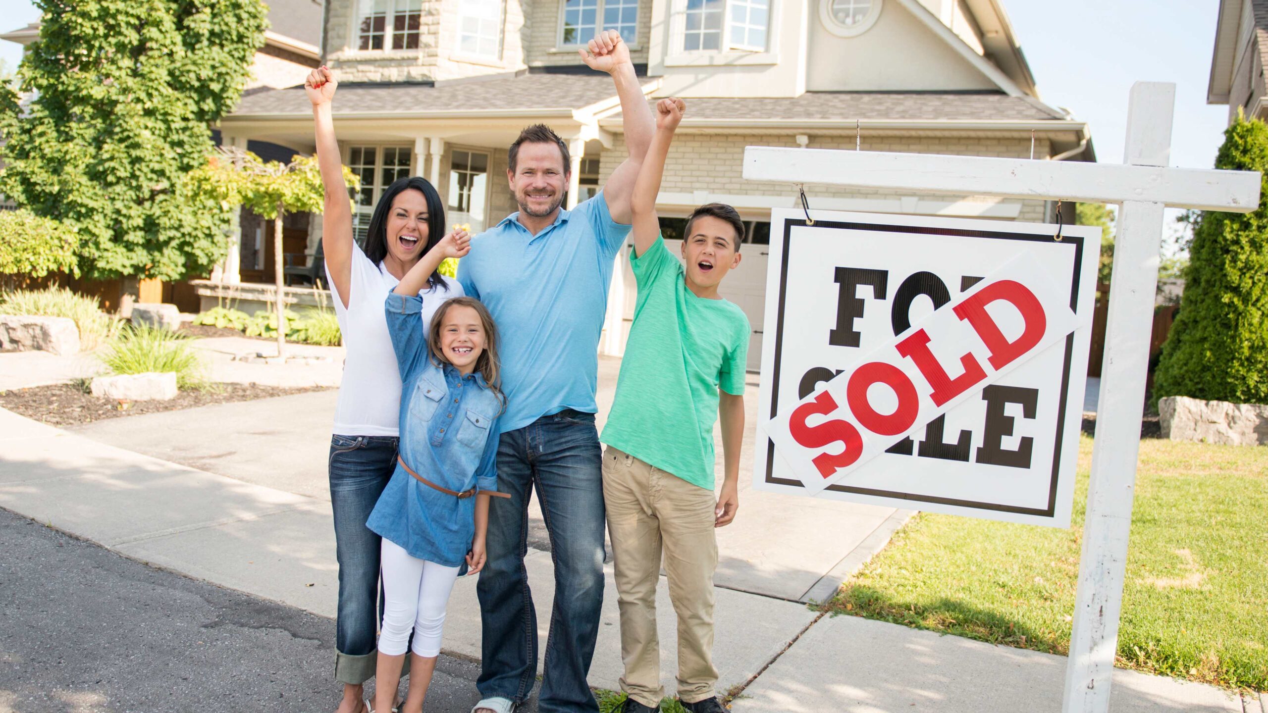 A family stands outside of their sold home in front of a recently cleaned driveway