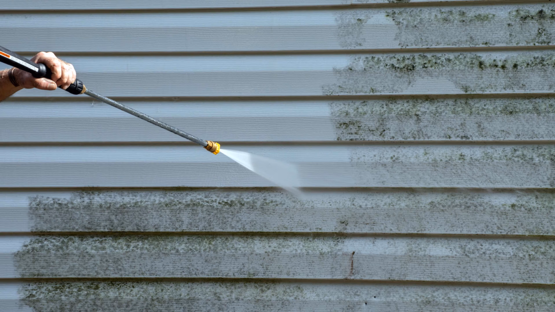 Pressure washing mold and mildew off of the side of a home in Tallahassee, Florida