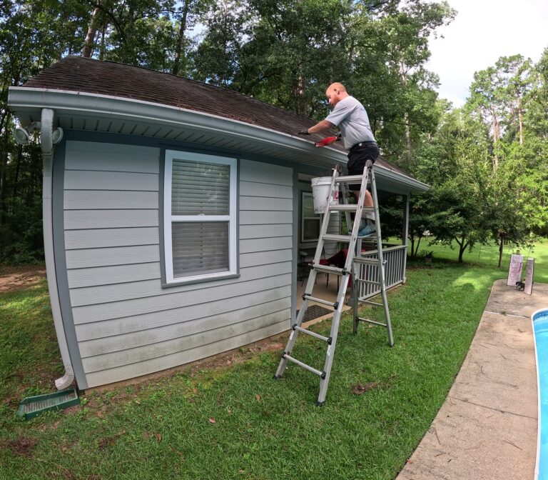 Roof Cleaning 5 Cleaning gutters at the roofline from a ladder in Tallahassee, FL